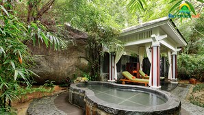 A hot spring area with a stone pool, lounge chairs, and a gazebo. - Nui Than Tai Ebisu Onsen Resort (Da Nang)