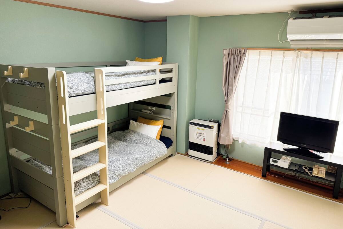 A bunk bed room with a desk, a television, and an air conditioner.