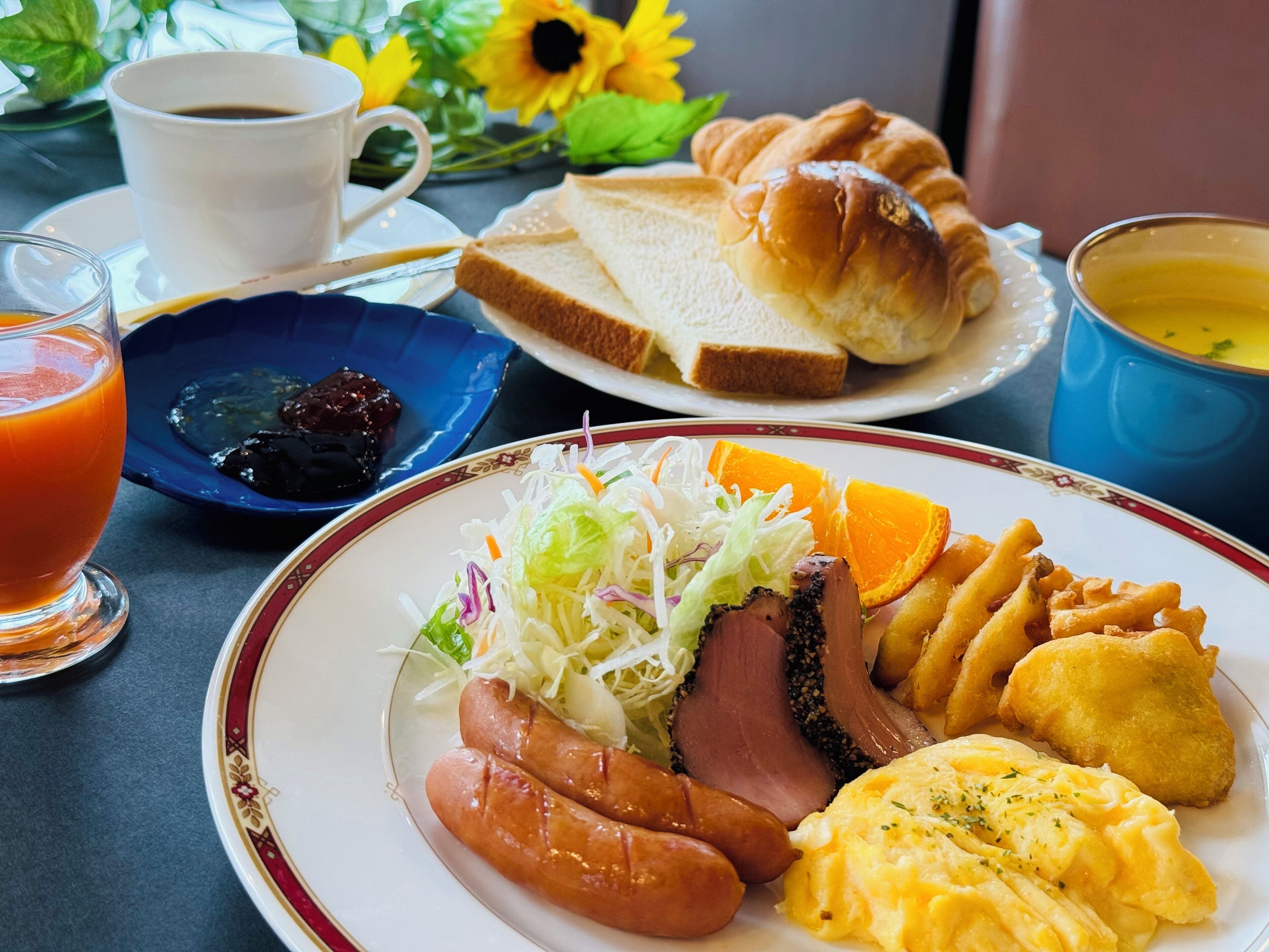 A breakfast plate with sausages, ham, eggs, and fried potatoes.