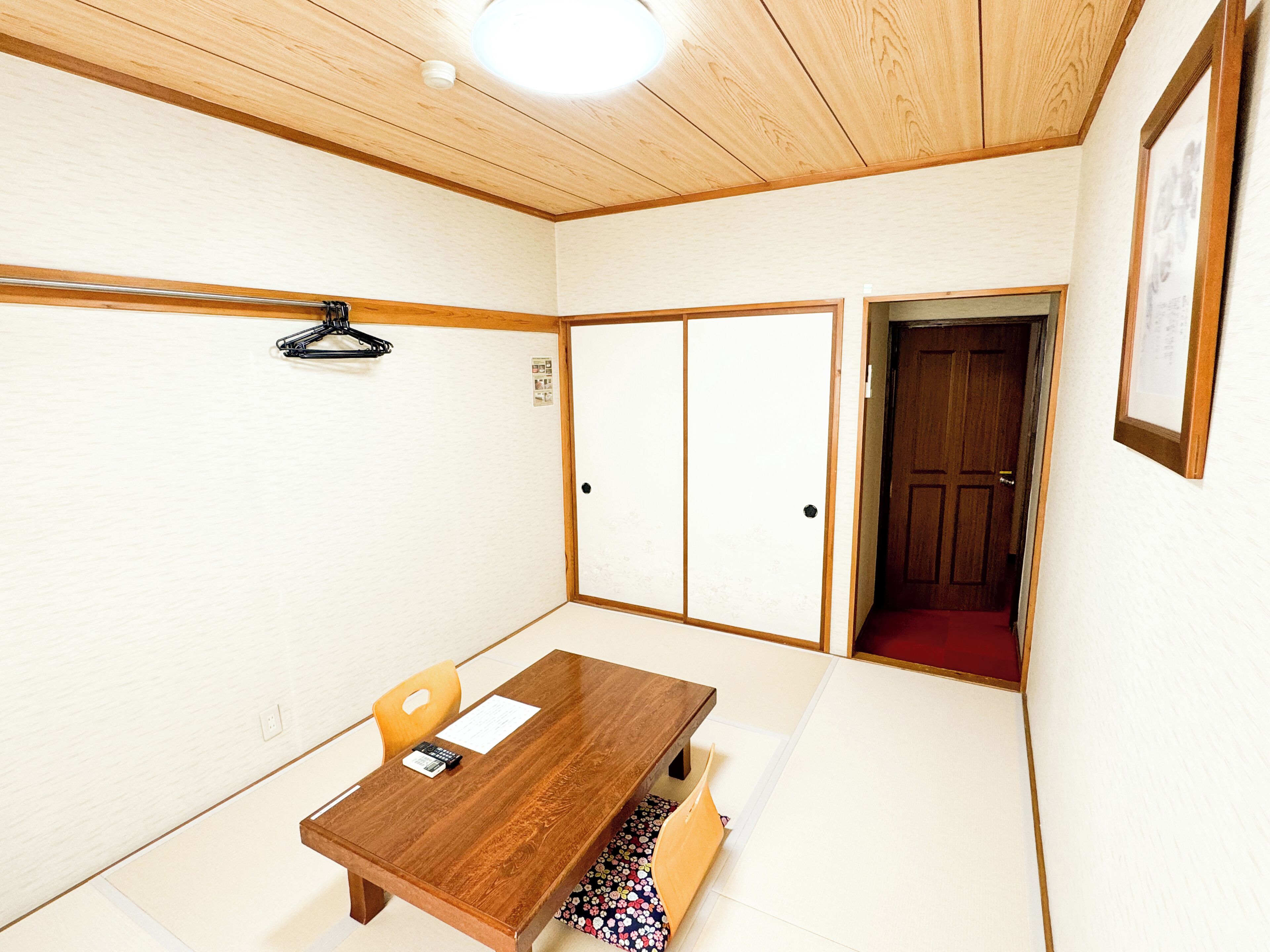 A room with a wooden table, chairs, a wardrobe, and a door.