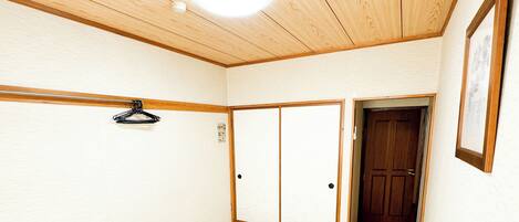 A room with a wooden table, chairs, a wardrobe, and a door.
