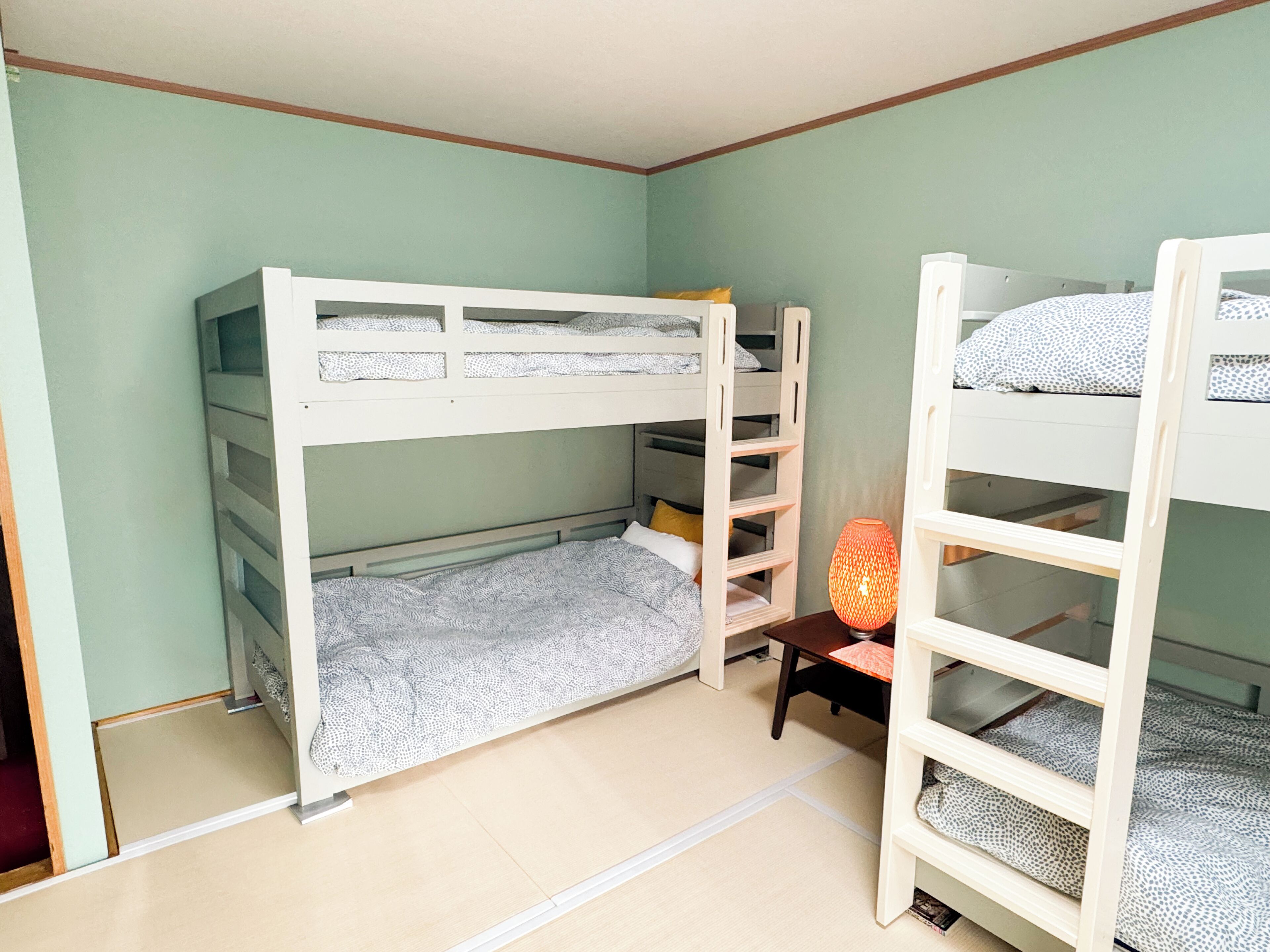 Una habitación con literas, una mesita y una lámpara.
