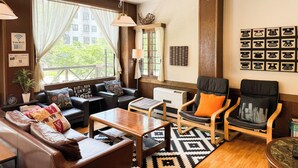 A cozy living room with a sofa, chairs, a coffee table, and a large window with curtains. - Belle Vue Nishiura (Minamiuonuma)
