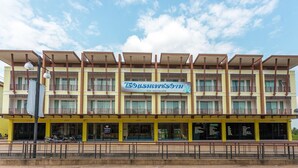 A multi-story hotel with a yellow facade, balconies, and a large sign in the center. - Phet Ngam Hotel (Mae Sai)