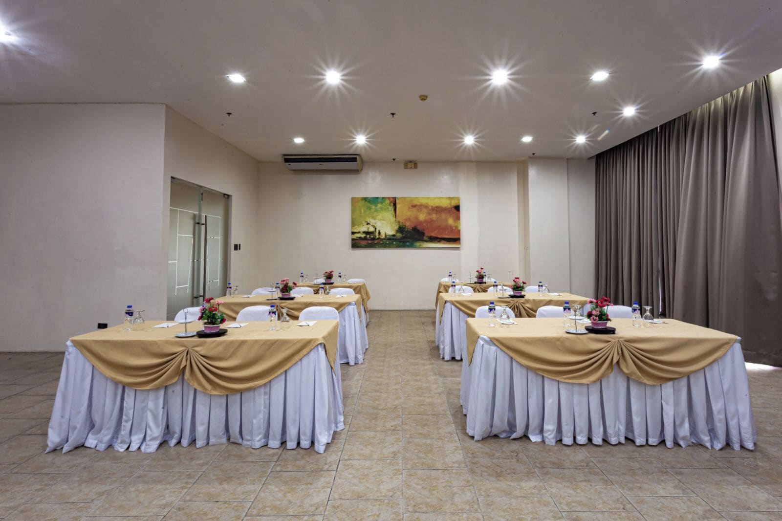 A conference room with tables set for meetings, equipped with nameplates, water bottles, and floral centerpieces.