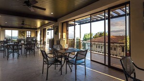 Ein geräumiger Innenbereich mit Balkon, großen Fenstern und Deckenventilatoren.