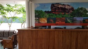 Una recepción con detalles de madera, un mural grande que representa diversos paisajes y escenas culturales, y un área de descanso con cojines estampados.