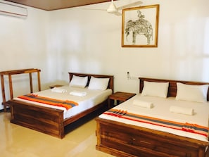 A hotel room with two wooden beds, white linens, and a colorful striped blanket. - Alikele Hotel Sigiriya (Inamaluwa)