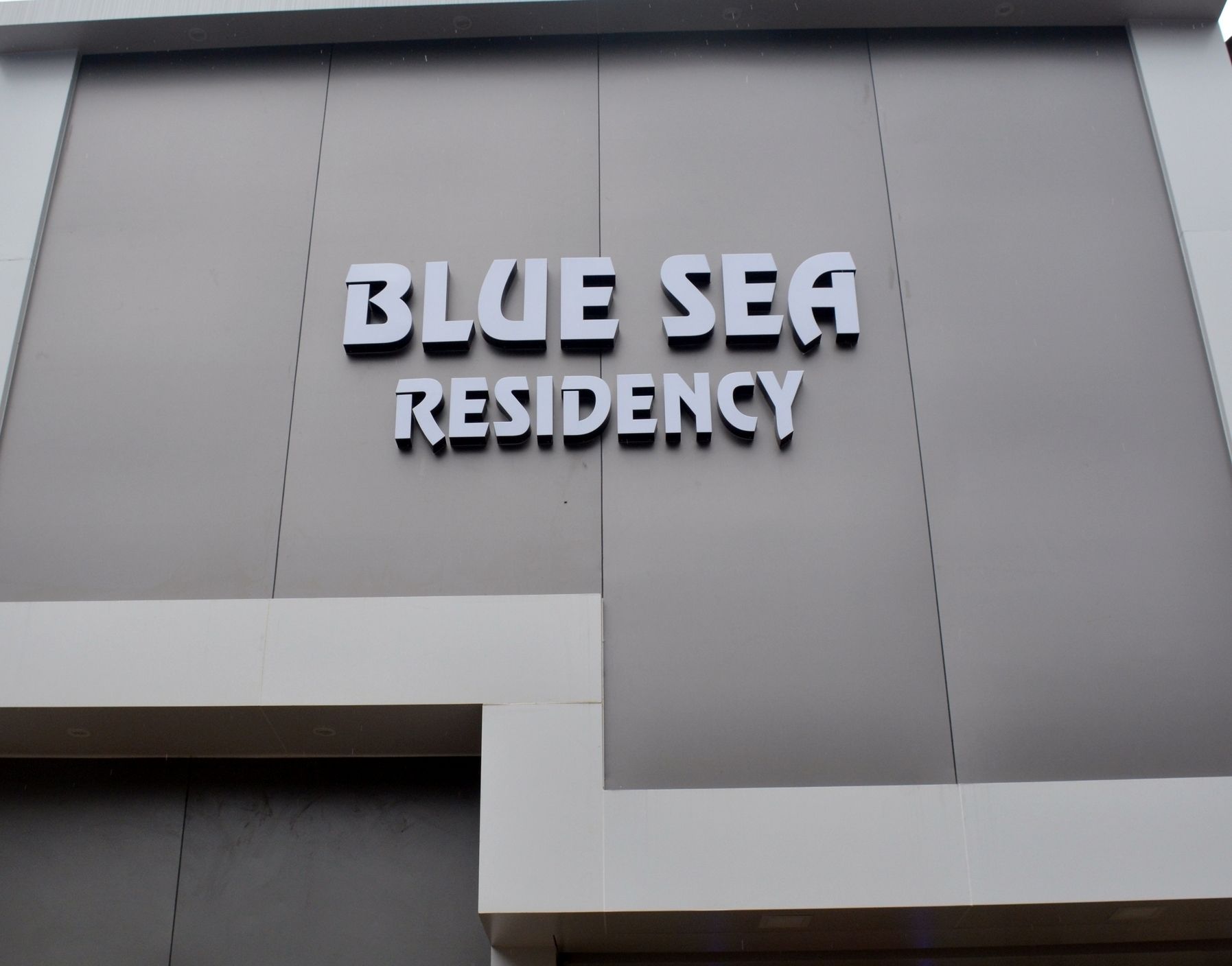 Un immeuble portant l’enseigne « BLUE SEA RESIDENCY », indiquant qu’il s’agit d’un immeuble résidentiel.