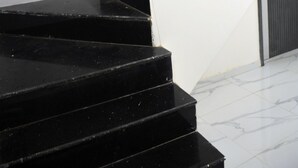 Degraus de mármore preto que levam a uma parede branca.