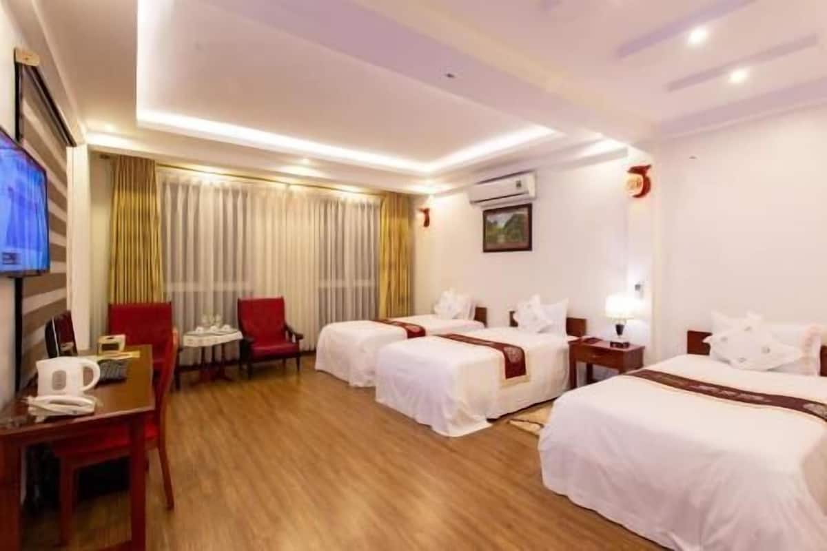 A hotel room with two beds, a desk, a chair, a TV, and a window with curtains.