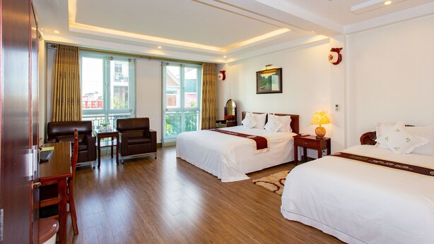 Habitación de hotel con dos camas, un escritorio, una silla y ventana con vista a edificios.