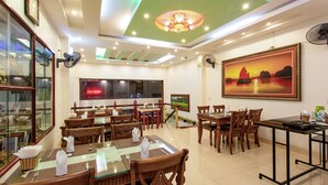 Un restaurante con mesas y sillas de madera, un ventilador de techo y un cuadro grande en la pared.