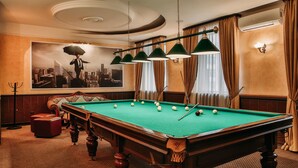 A pool table in a room with a cityscape mural, a candelabra, and a chandelier.