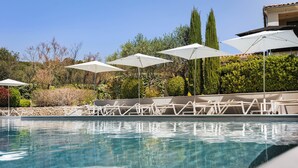 A swimming pool with white umbrellas and lounge chairs. - Hôtel b design & Spa (Paradou)
