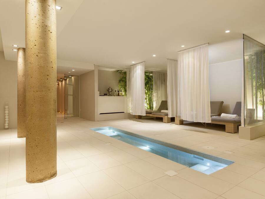 Un moderno espacio de spa con piscina, asientos y vegetación.