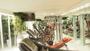 A gym with exercise equipment, a treadmill, and a mirrored wall.