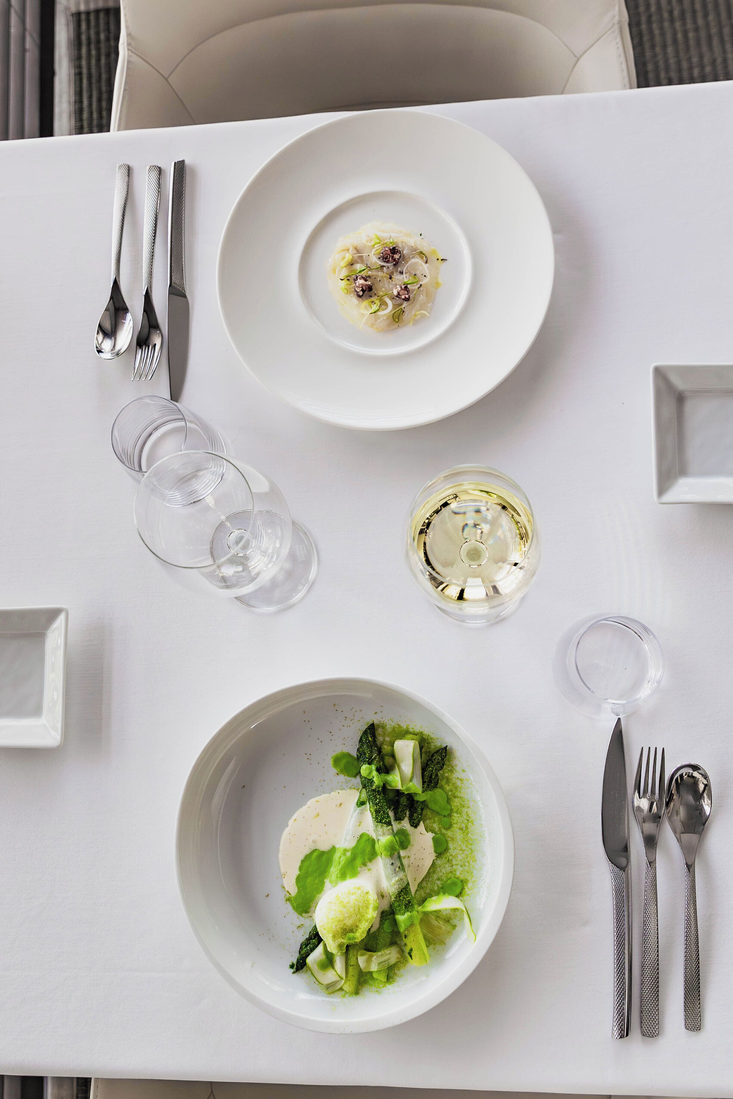 A dining table with two plates of food, cutlery, and glasses.