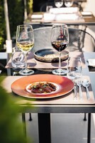 Uma mesa de jantar com um prato de comida, duas taças de vinho e talheres.