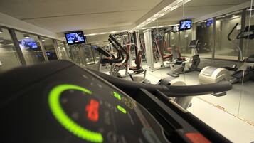 Une salle de sport équipée de matériel d’exercice, notamment des tapis de course et des appareils de musculation, ainsi que des miroirs aux murs.
