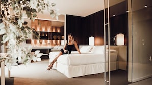 A modern hotel room with a large bed, a desk, and a glass partition. - Hôtel b design & Spa (Paradou)