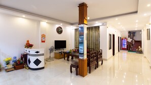 A spacious living area with a television, a wooden coffee table, and a decorative pillar. - Ngoc Anh Legend Hotel (Ninh Binh)