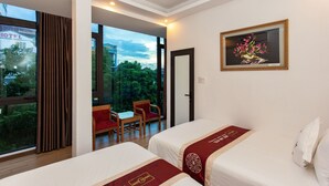 A hotel room with two beds, a dining area with a table and chairs, and a large window offering a view of the outdoors. - Ngoc Anh Legend Hotel (Ninh Binh)