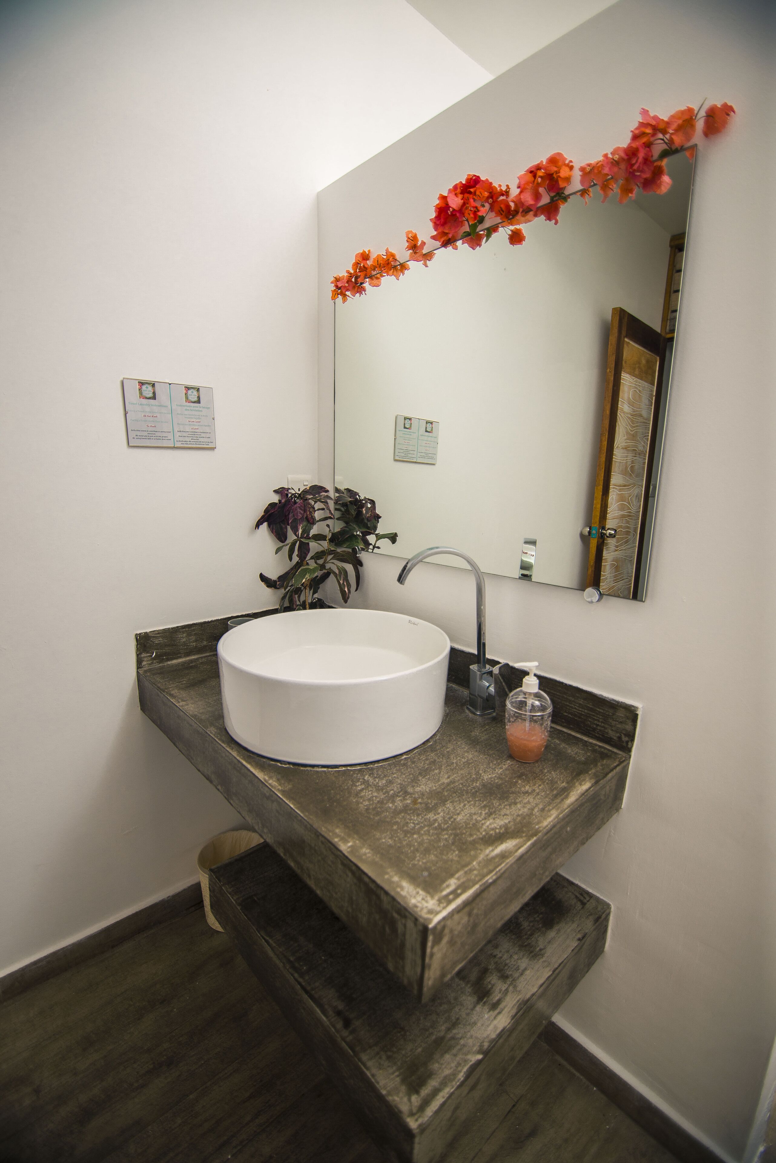 A bathroom with a white sink, a mirror, and a wooden countertop.