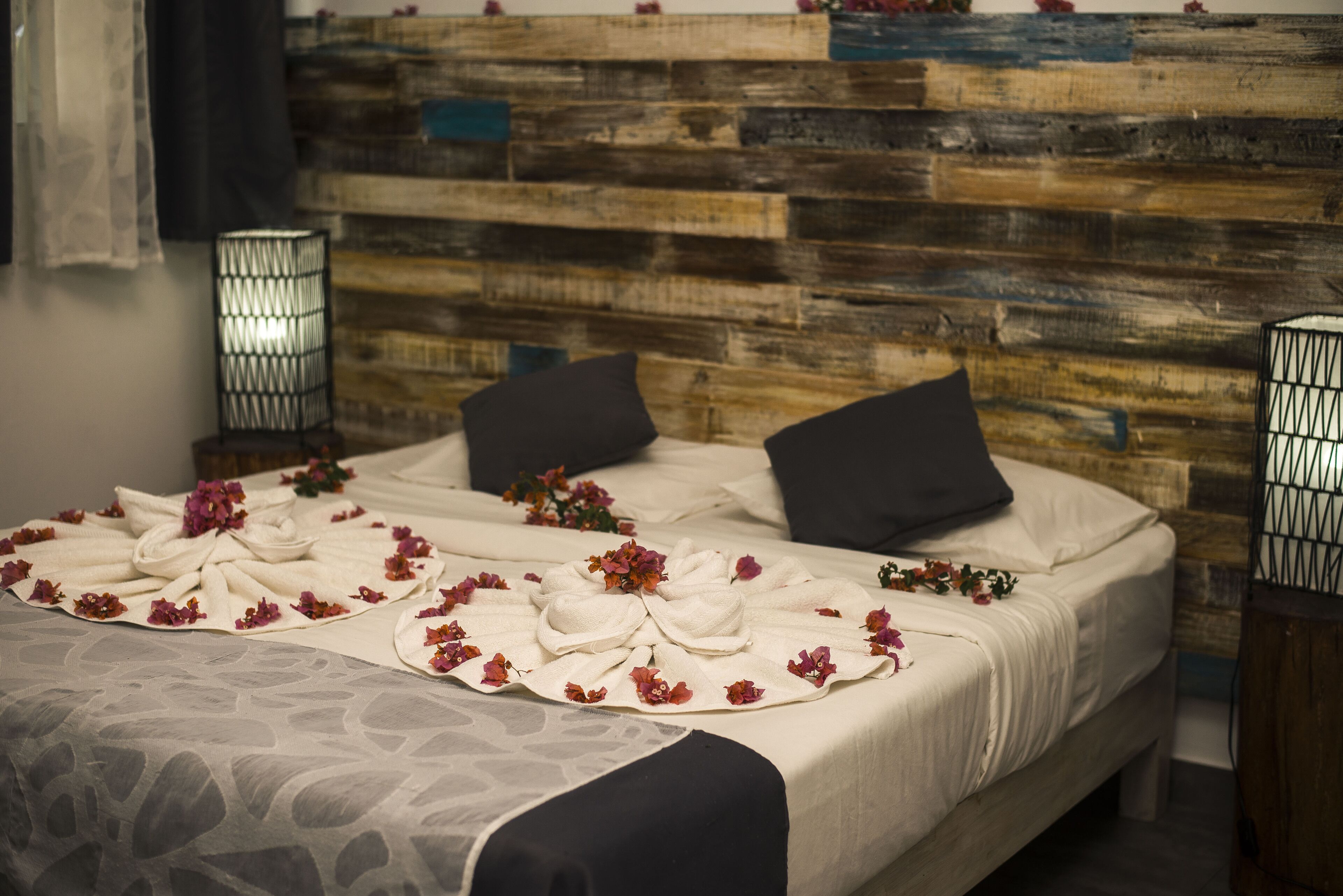 Una cama con cabecera de madera, ropa de cama blanca y almohadas decorativas.