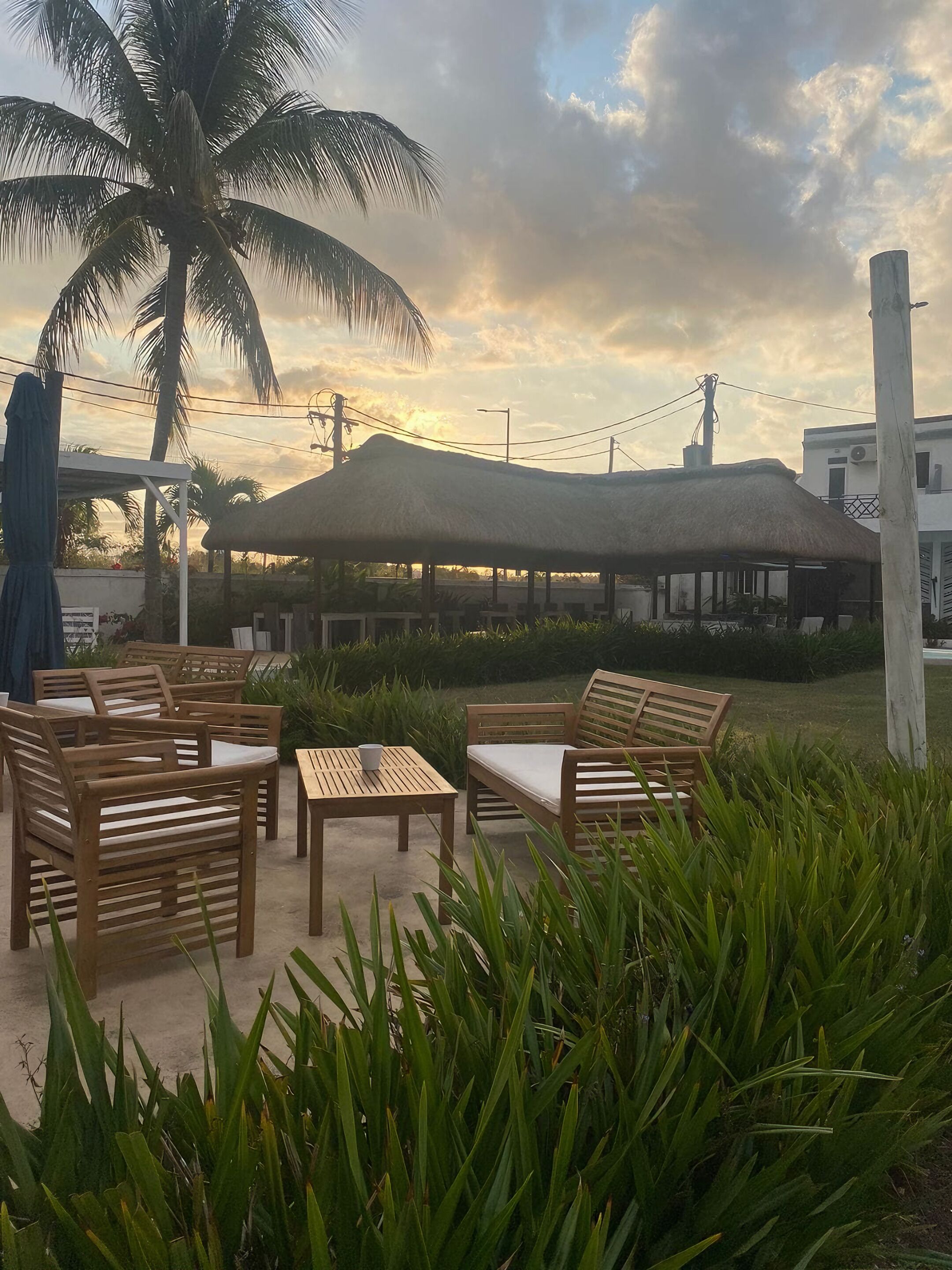 An outdoor seating area with wooden furniture and a thatched-roof structure.