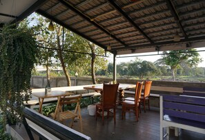 An outdoor patio with a table and chairs, surrounded by greenery and a view of the landscape. - Siya House Hotel Chiangrai (Chiang Rai)