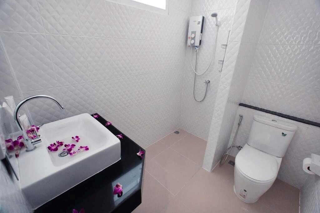 A bathroom with a white sink, a toilet, and a shower.