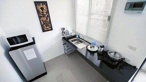 Une cuisine compacte équipée d’un four à micro-ondes, d’un évier et d’une fenêtre avec des stores.