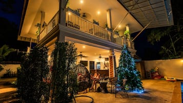 A two-story house with a balcony, outdoor seating area, and a Christmas tree.