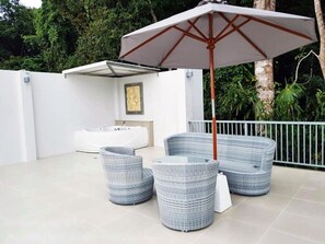 A modern outdoor seating area with wicker furniture and a large umbrella. - Lux Family Villas (Krabi)