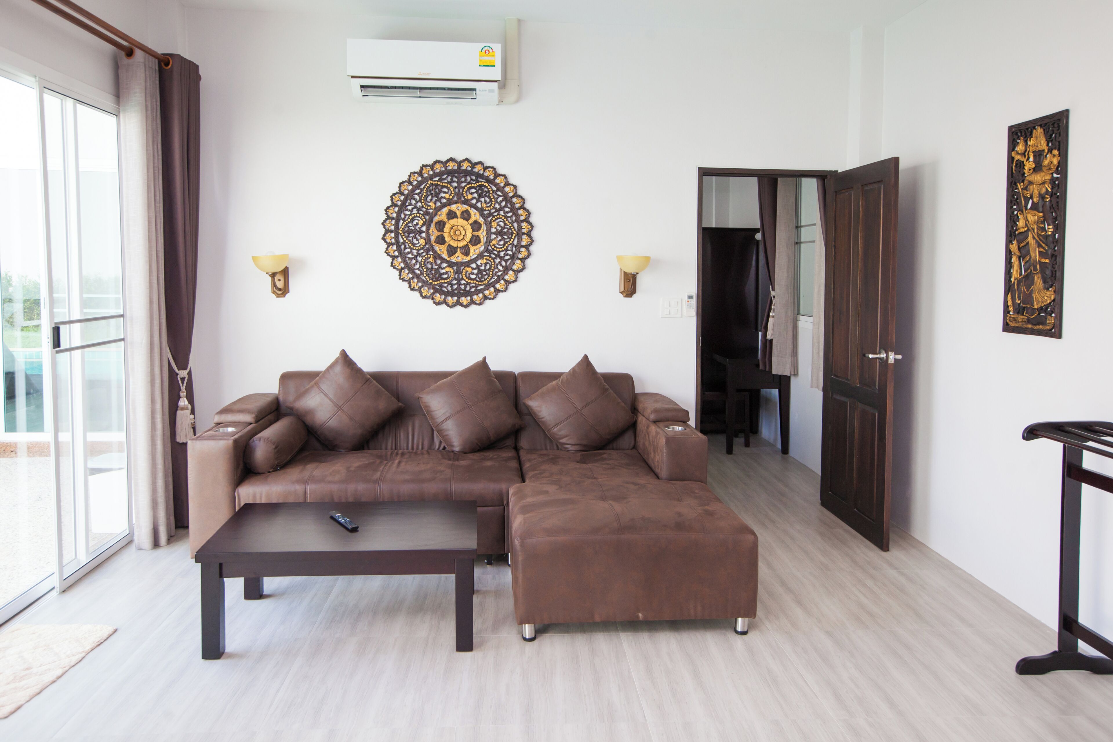 A living room with a sectional sofa, a coffee table, wall-mounted lamps, and a decorative wall piece.