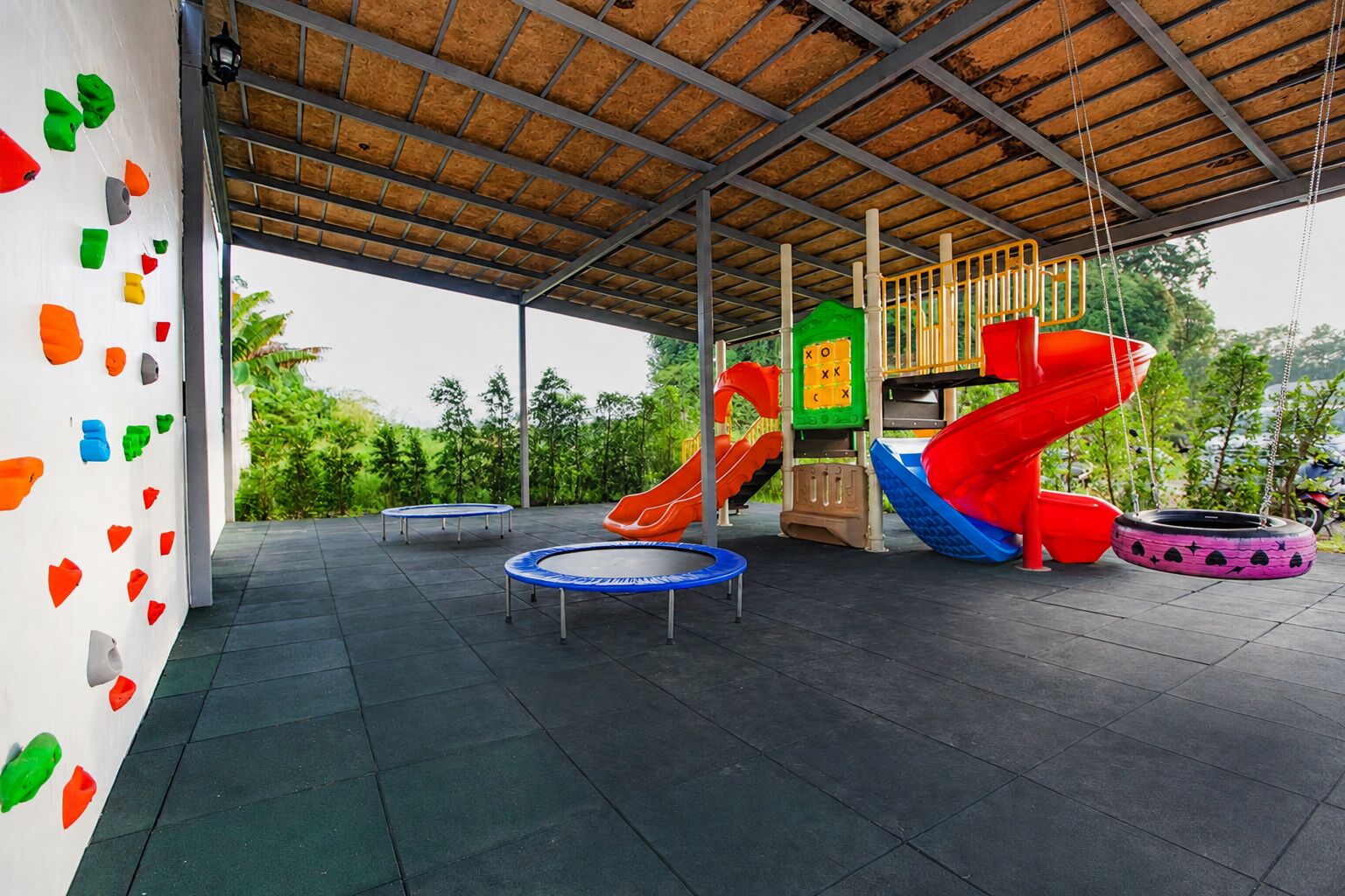 Zona de juegos al aire libre con tobogán, muro de escalar y columpios.