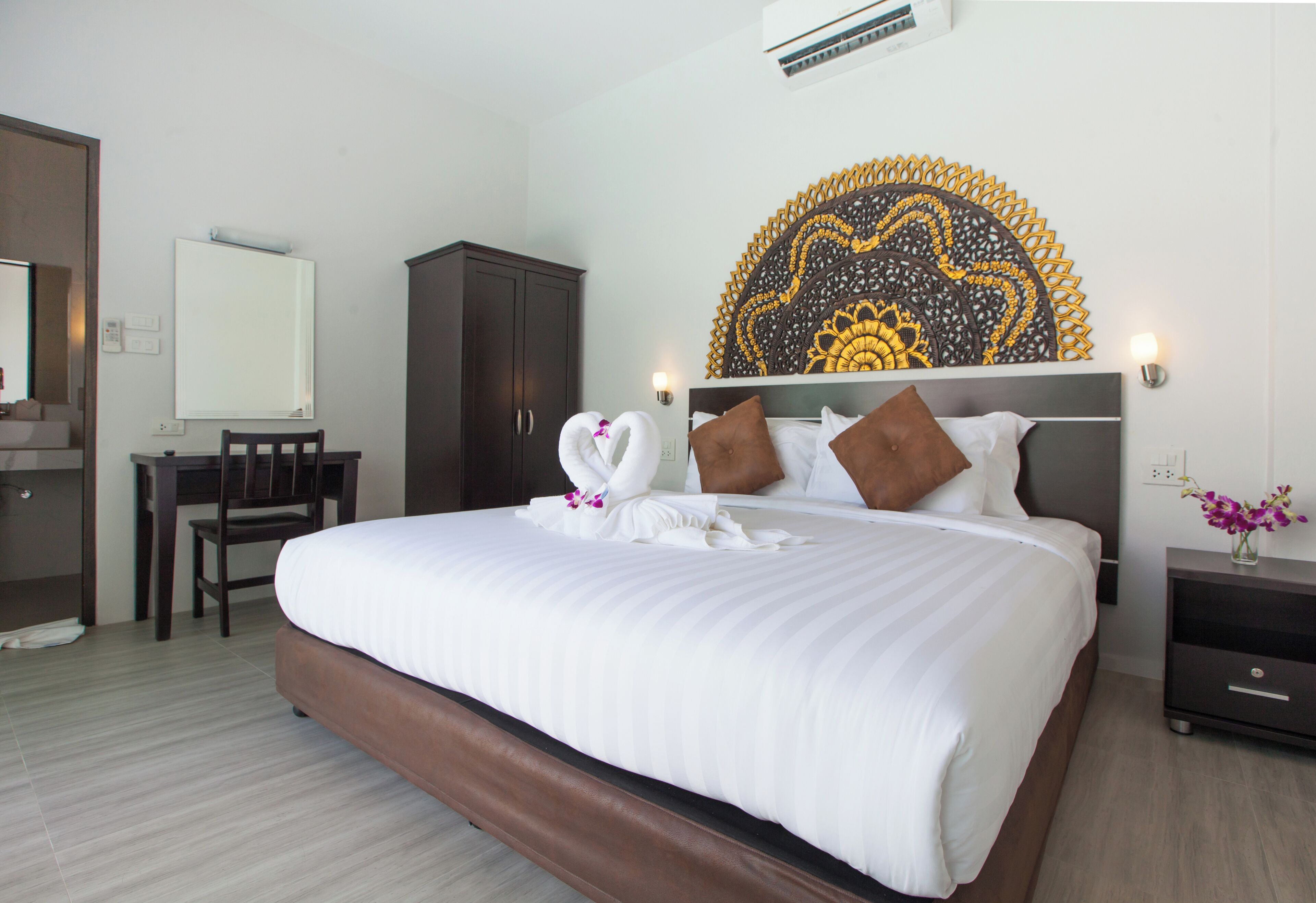 Une chambre d’hôtel avec un grand lit, un bureau, une armoire et une tête de lit décorative.