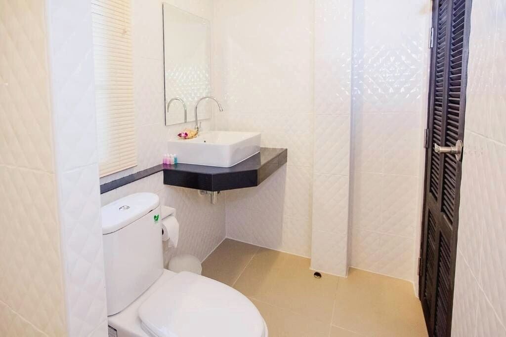 Ein kleines Badezimmer mit Toilette, Waschbecken mit Spiegel und Duschbereich mit Vorhang.