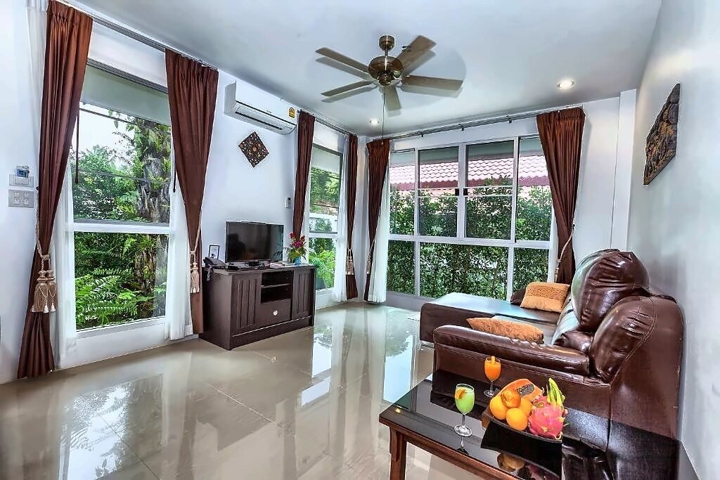 A modern living room with a leather sofa, a flat-screen TV, and a coffee table with fruit.