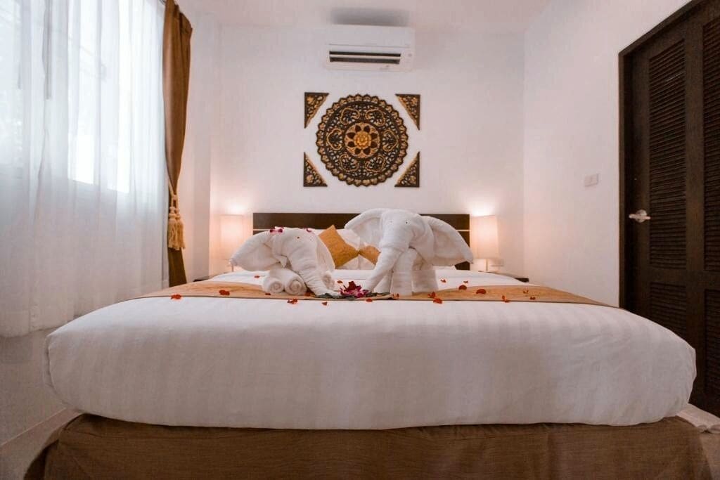 A hotel room with a bed, a decorative wall piece, and an air conditioning unit.