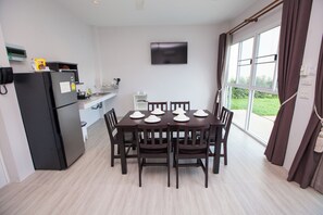 Una cocina moderna con refrigerador, microondas y comedor con mesa preparada para seis.