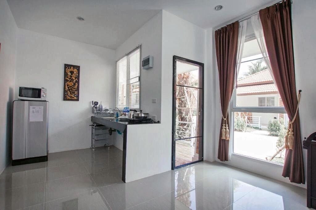 A modern kitchen with a microwave, a sink, and a window with curtains.