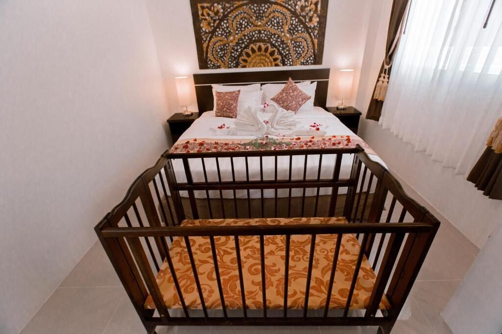 A bedroom with a bed, a nightstand, a decorative wall piece, and a crib.
