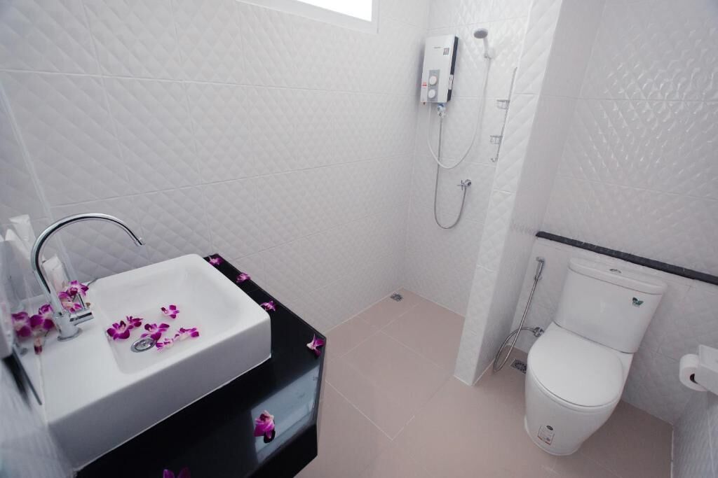 Un baño con lavamanos blanco, inodoro y ducha.