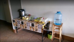 Una zona de cocina con una mesa temática de café, un dispensador grande de agua y un cubo de basura.