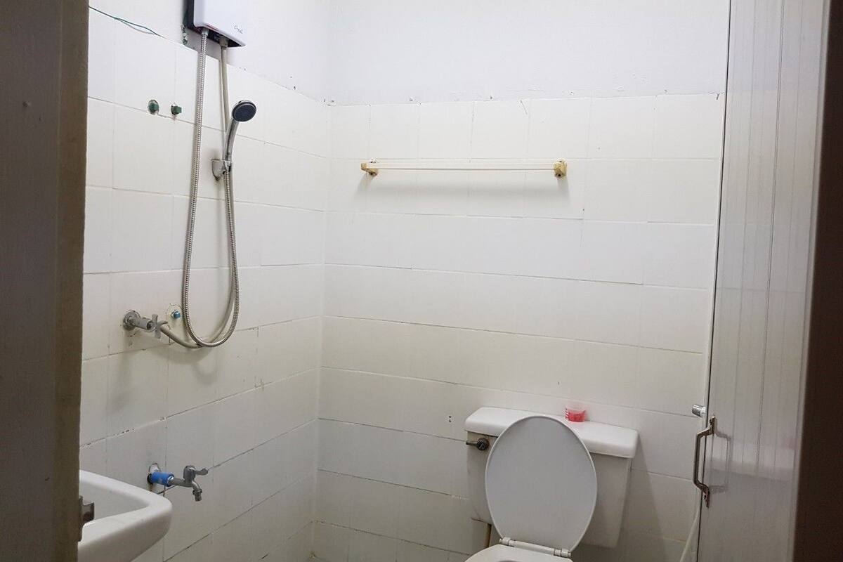 A small, basic bathroom with a toilet, a sink, and a shower.
