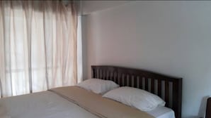 Habitación de hotel con cama, cortinas y una pared lisa.