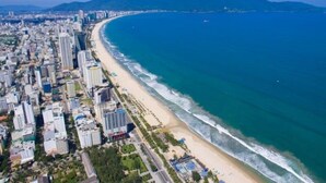 An aerial view of a coastal city with a long beach, high-rise buildings, and mountains in the background. - Ocean Star Da Nang Bay Hotel (Da Nang)