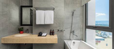 A modern bathroom with a large bathtub, a sink with a mirror above it, and a shower.